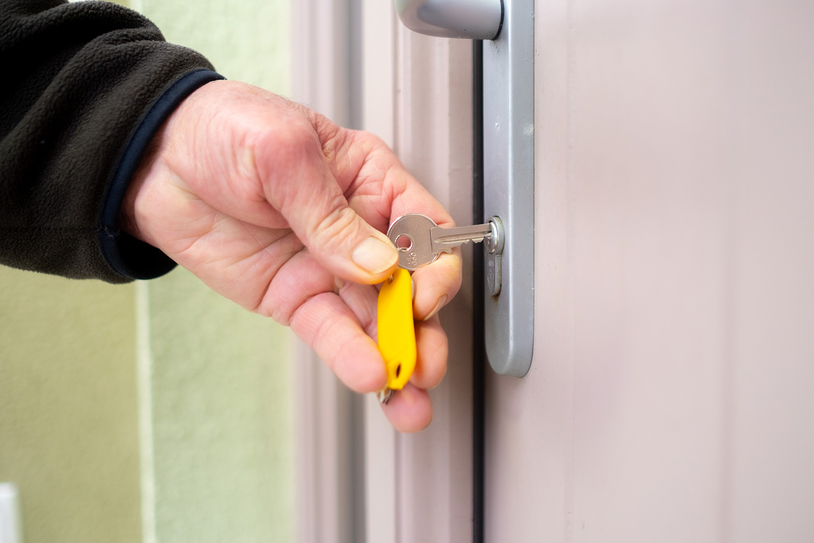 Man's hand inserting key in lock.